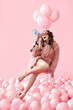 © GVS - Trendy young woman shouting in megaphone on pink balloons background
