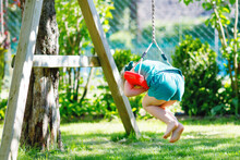 Happy Little Preschool Girl Having Fun On Swing In Domestic Garden. Healthy Toddler Child Swinging On Sunny Summer Day. Children Activity Outdoor, Active Smiling Kid Laughing