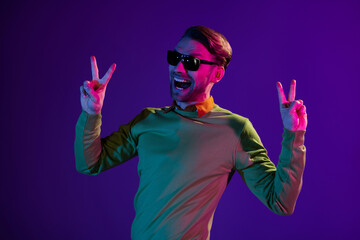 Sticker - Photo portrait of man in nightclub showing v-sign gesture funny isolated on purple color background