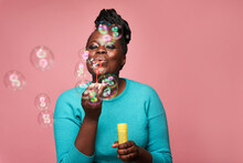 Joyful Black Woman Blowing Soap Bubbles In Studio