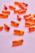 Orange Pills Scattered On Pink Surface