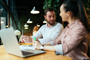 Colleagues discussing details of job while working on laptop