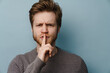 © Drobot Dean - White ginger man with beard showing silence gesture at camera