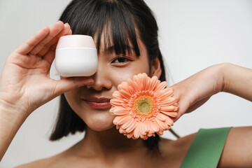 Wall Mural - Young asian woman posing with face cream and gerbera flower