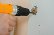 © sun_house_ann - a man tightens a screw with a screwdriver in a door hinge on a white cabinet door