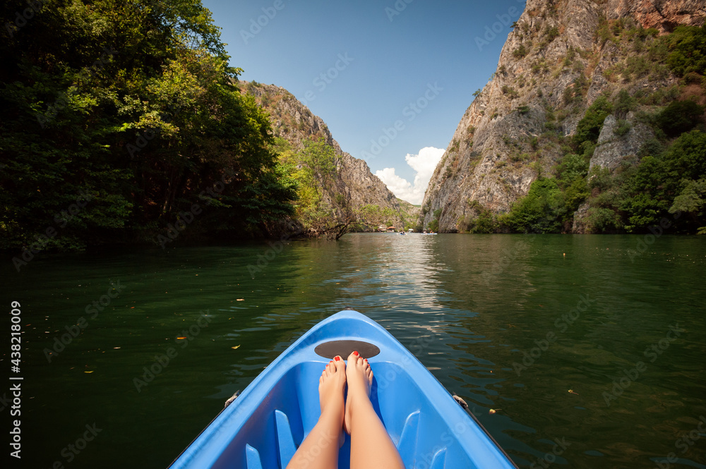 Kayaking through river in Matka canyon, Macedonia. Woman legs in the blue kayak - obrazy, fototapety, plakaty 