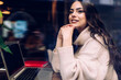 © BullRun - Smiling young woman with laptop in cafe