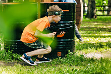 Armed Teenager Boy Playing In Laser Tag Shooting Game Outdoors