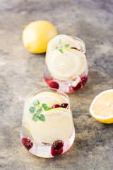 Summer refreshing cold cocktail with lemon, lemon balm and cherry - hard seltzer in glasses on the table. Vertical view