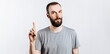 © Daria Lukoiko - Portrait of cheerful young handsome man smiling looking at camera pointing finger upwards on white background with space for advertising mock up