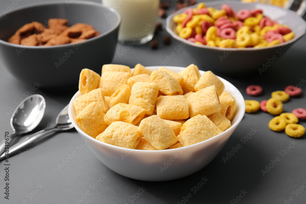 Bowls with different cereals on dark background, closeup