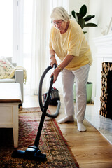 Wall Mural - Senior woman vacuuming a carpet