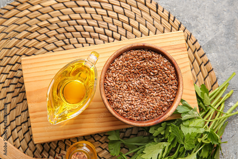 Composition with flax seeds, oil and parsley on grey background