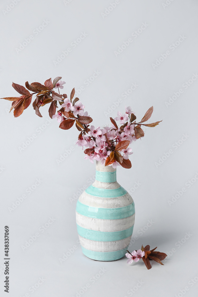 Vase with beautiful blossoming branches on grey background