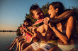 © Zoran Zeremski - Friends sitting on the edge of a pier enjoying on a summer day at the lake eating watermelon.