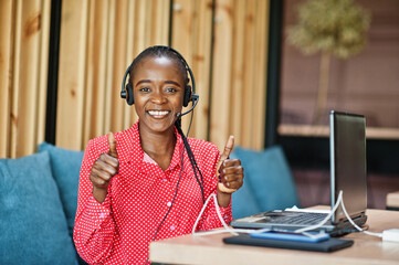 African american woman works in a call center operator and customer service agent wearing microphone headsets working on laptop.