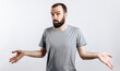 © Daria Lukoiko - Portrait of a cheerful young man smiling while looking at the camera, throwing up his hands to the sides from ignorance on a white background with a place for advertising mockup