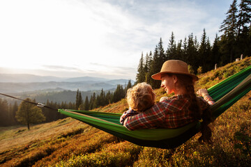 Wall Mural - Boy tourist resting in a hammock in the mountains at sunset