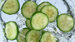 sliced cucumber splashing water isolated on white background, macro shot.