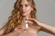Half-naked white ginger woman posing with face serum