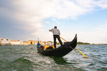 Unrecognizable Gondolier Man Rowing In Venice Channels.