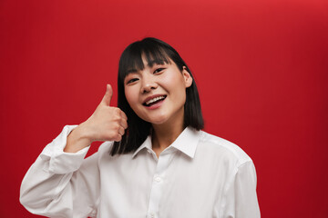 Wall Mural - Young asian woman wearing shirt smiling and showing thumb up