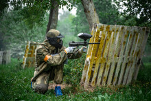 A Player Behind Cover Shooting On A Paintball Battlefield