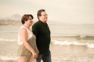 lifestyle portrait of loving happy and sweet mature couple - senior retired husband and wife on 70s enjoying beach walk relaxed and cheerful celebrating love together