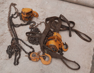 orange hook with sling belt and chain block or chain hoist which is placed on a cement floor, usuall