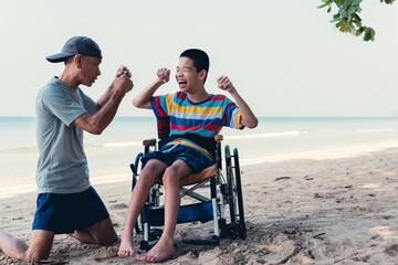 Wall Mural - Disabled child on wheelchair playing sports for man with father on blue sea beach, Lifestyle of disability kid is a healthy and good mood in relaxing travel holidays with love in disabilities family.