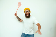 Young Caucasian Hipster Man Holding A Fly Swatter Wanting To Kill Annoying Mosquito Or A Fly.