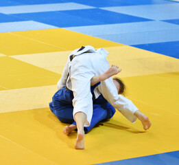 Two Girls judoka in kimono compete on the tatami 