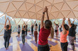© ADDICTIVE STOCK - People stretching up with raised hands on yoga mats in domed hal