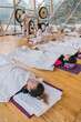© ADDICTIVE STOCK - Spiritual woman hitting gong while calm people lying on yoga mats with eyes closed in yoga class
