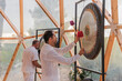 © ADDICTIVE STOCK - People in white robes hitting gong in bright room