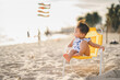 baby in white dress sit on the chair beach yellow color with relaxing and the wind blows in evening time and beautiful sunset light