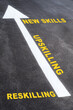 © smshoot - Newskills, upskilling and reskilling with white arrow sign marking on road surface for giving direction. Growth mindset concept and self improvement idea