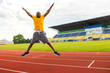 © shunevich - Full length photo of handsome afro american black sportsman jump high up wear shorts, sneakers and yellow t-shirt at the stadium, doing morning exercises or celebrating victory, goal, successful match
