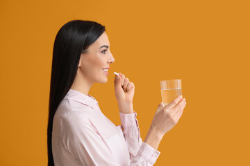 Wall Mural - Beautiful young woman with pills on color background