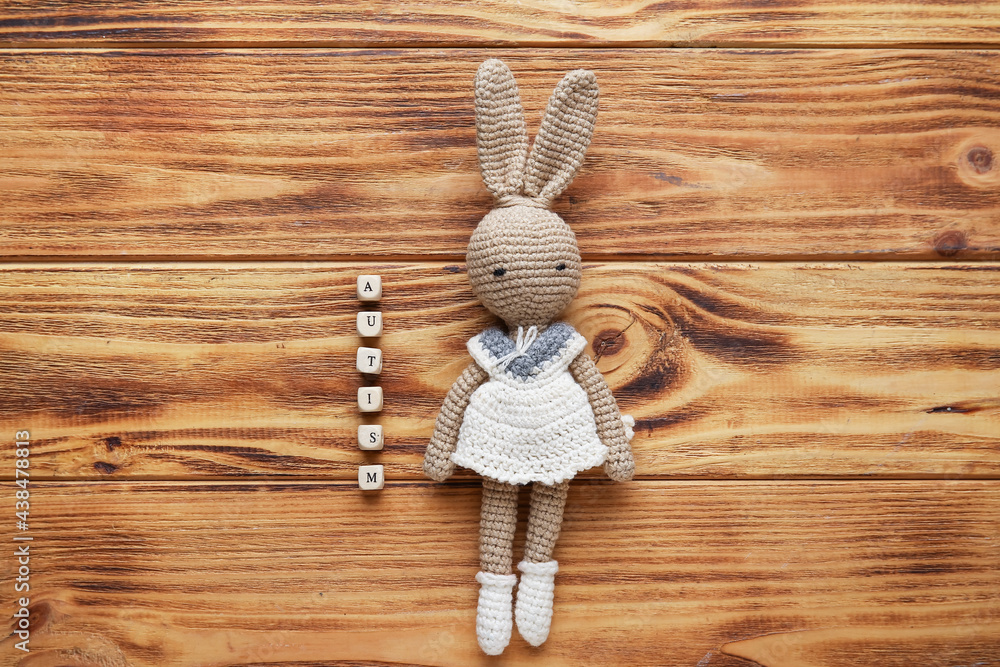 Word AUTISM and toy on wooden background