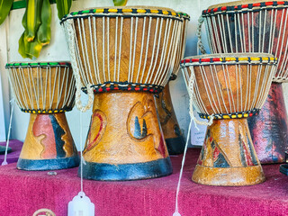 Various size djembes sitting on a shelf with on sale tags 