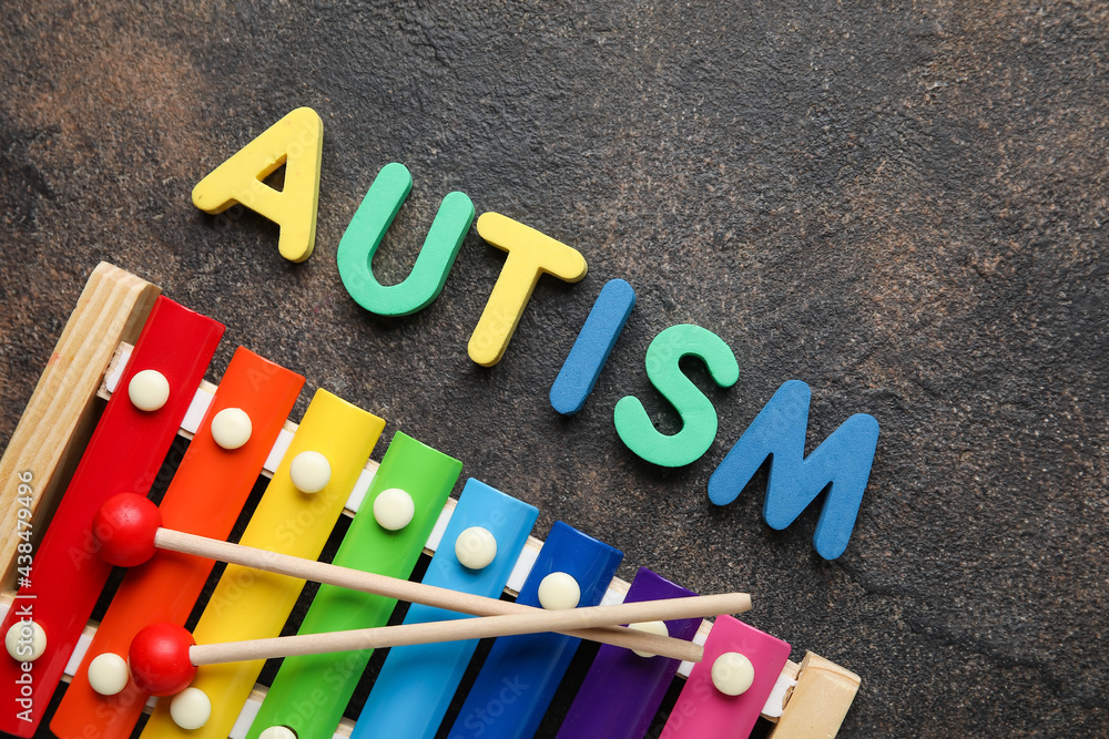 Word AUTISM and xylophone on grunge background