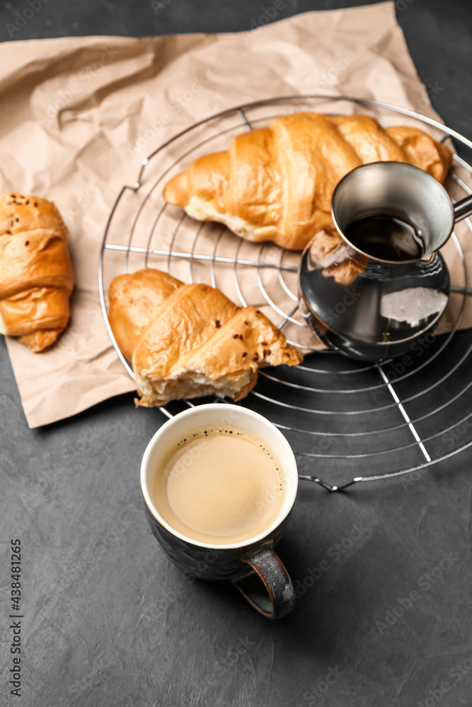 Pot, cup of coffee and croissant on dark background