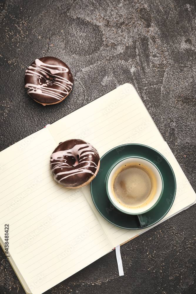 Cup of freshly brewed coffee and donuts on dark background