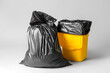 Bag with garbage and rubbish bin with logo of recycling on grey background