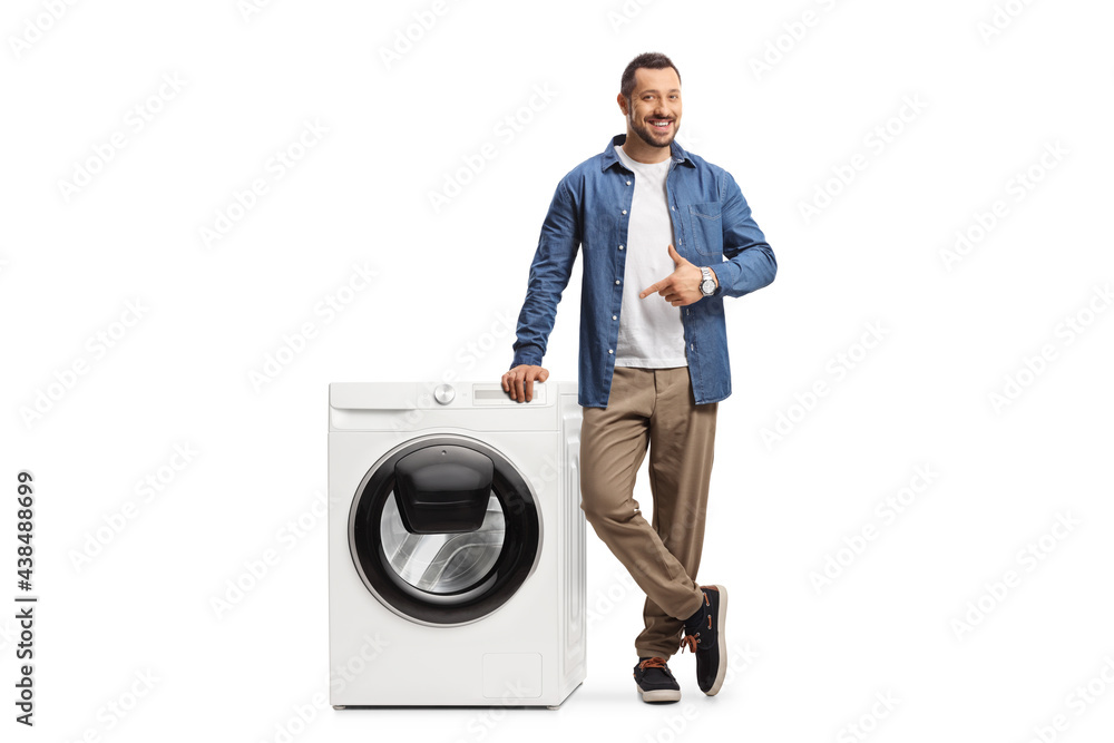 Young man leaning on a washing machine and pointing