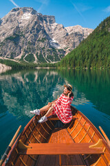 Wall Mural - woman sitting in big brown boat at lago di braies lake in Italy