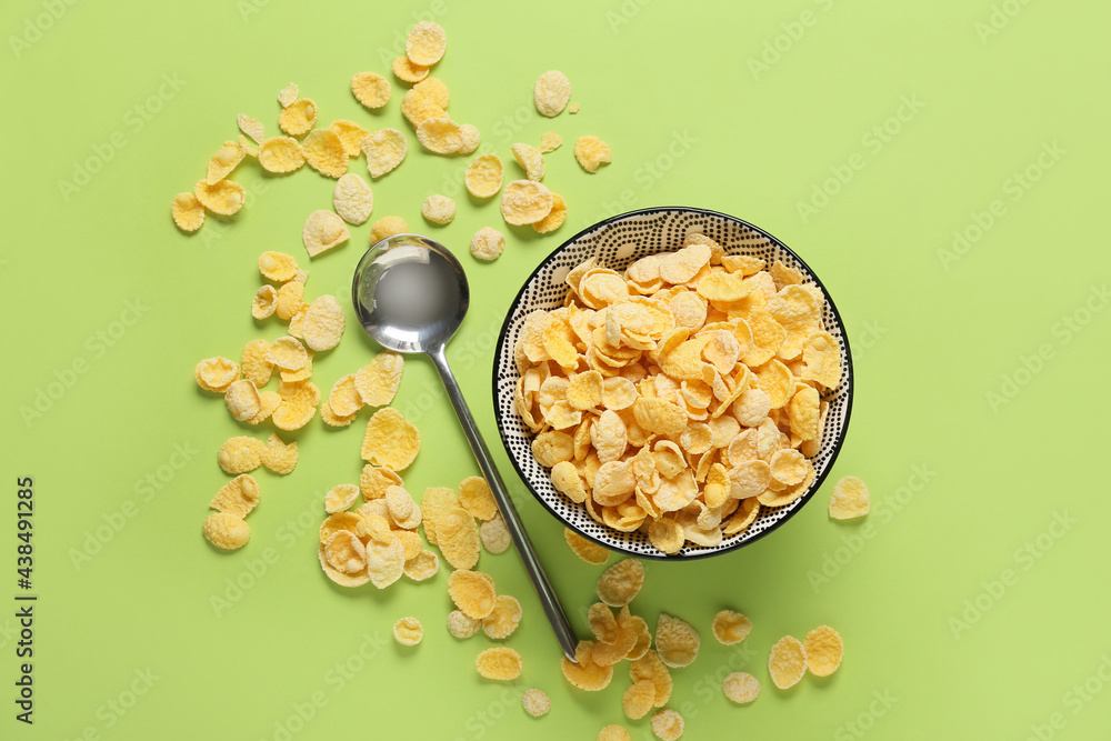 Bowl with tasty corn flakes on color background