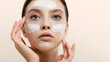 © jutaphoto - Young woman applying face cream or facial mask at her face. Beauty model with perfect fresh skin and long eyelashes cares about her skin at home