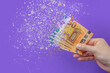 inflation euro . Inflation in Europe, hyper inflation. Banner with purple background. Fifty euro banknotes sprayed in the hand of a man on a purple background.